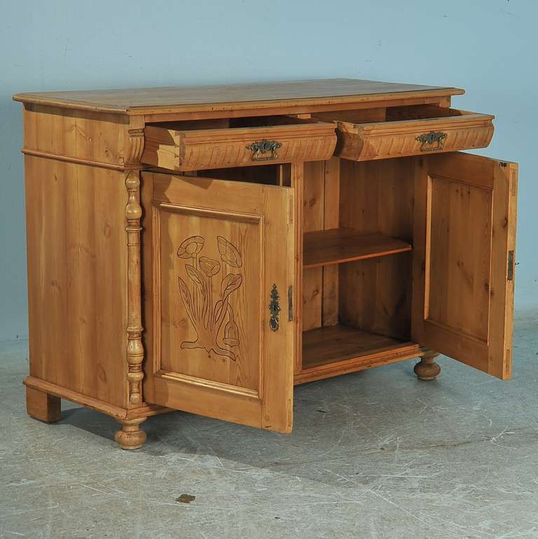 European country charm exudes from this pine sideboard from Denmark. The exquisite turned column details and floral carving in the panel doors add to the visual appeal of this sideboard. It has been given a wax finish, bringing out the warmth of the