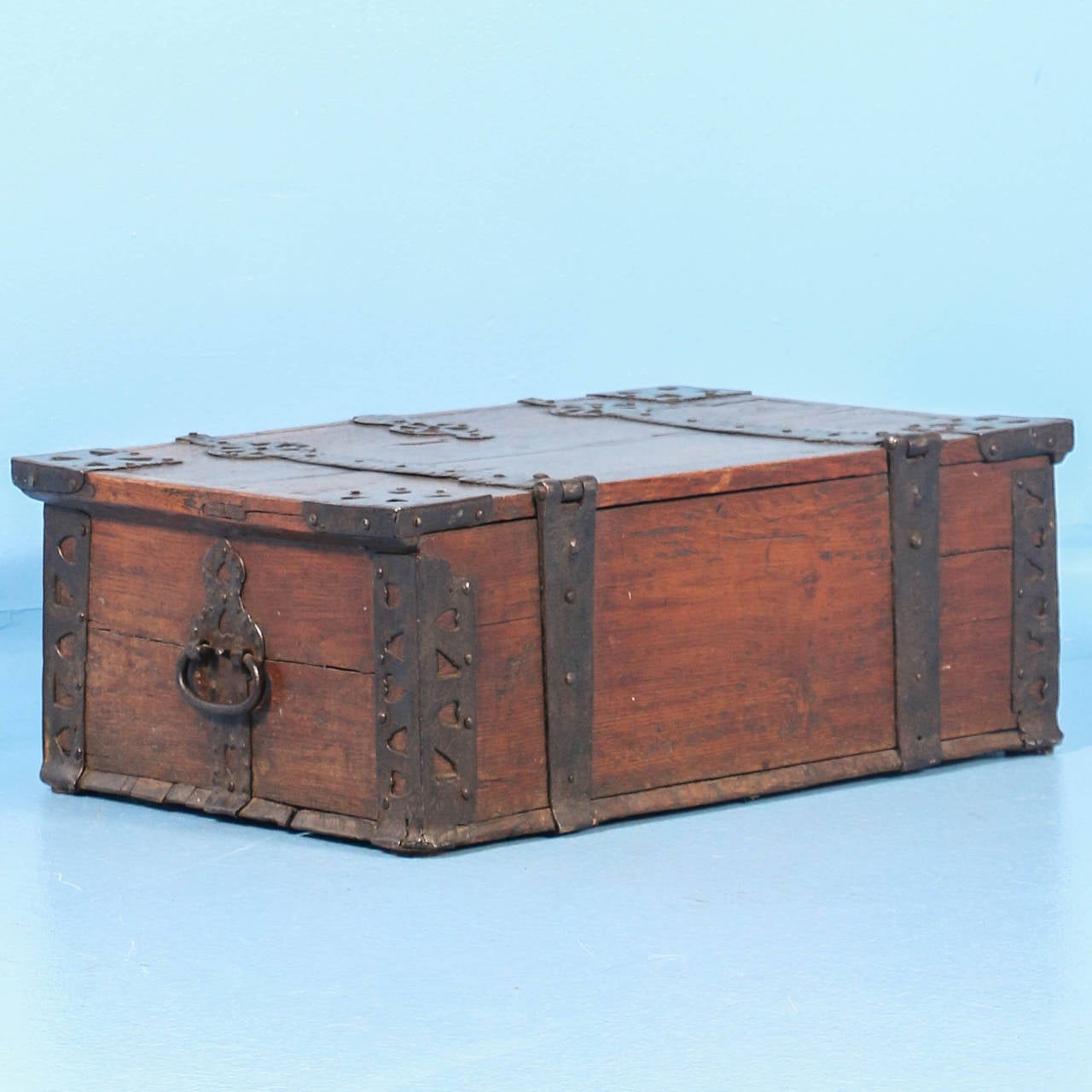 This small trunk or chest is heavily embellished with hand-wrought iron details, including cut-out of heart patterns. It originally serves as a money box to store and lock away valuables. Unique to this oak trunk is the original painted