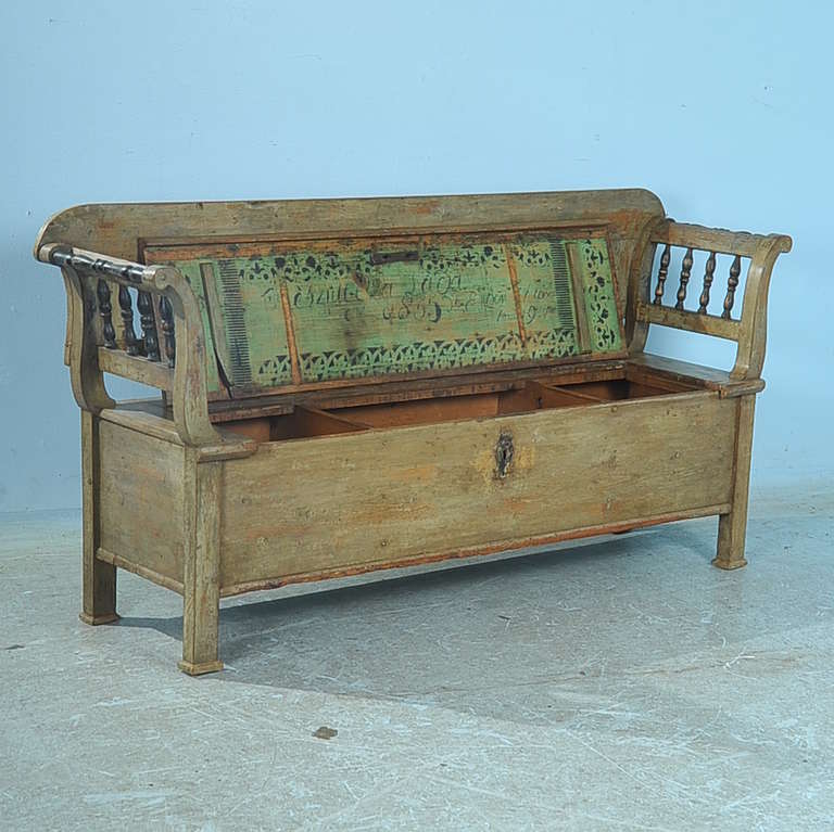 The remarkable celadon green paint on this bench is all original and a rare find. The patina has been worn down to aged perfection, note the wear on the bench seat that reveals the natural pine wood beneath. The turned black spindles that form the