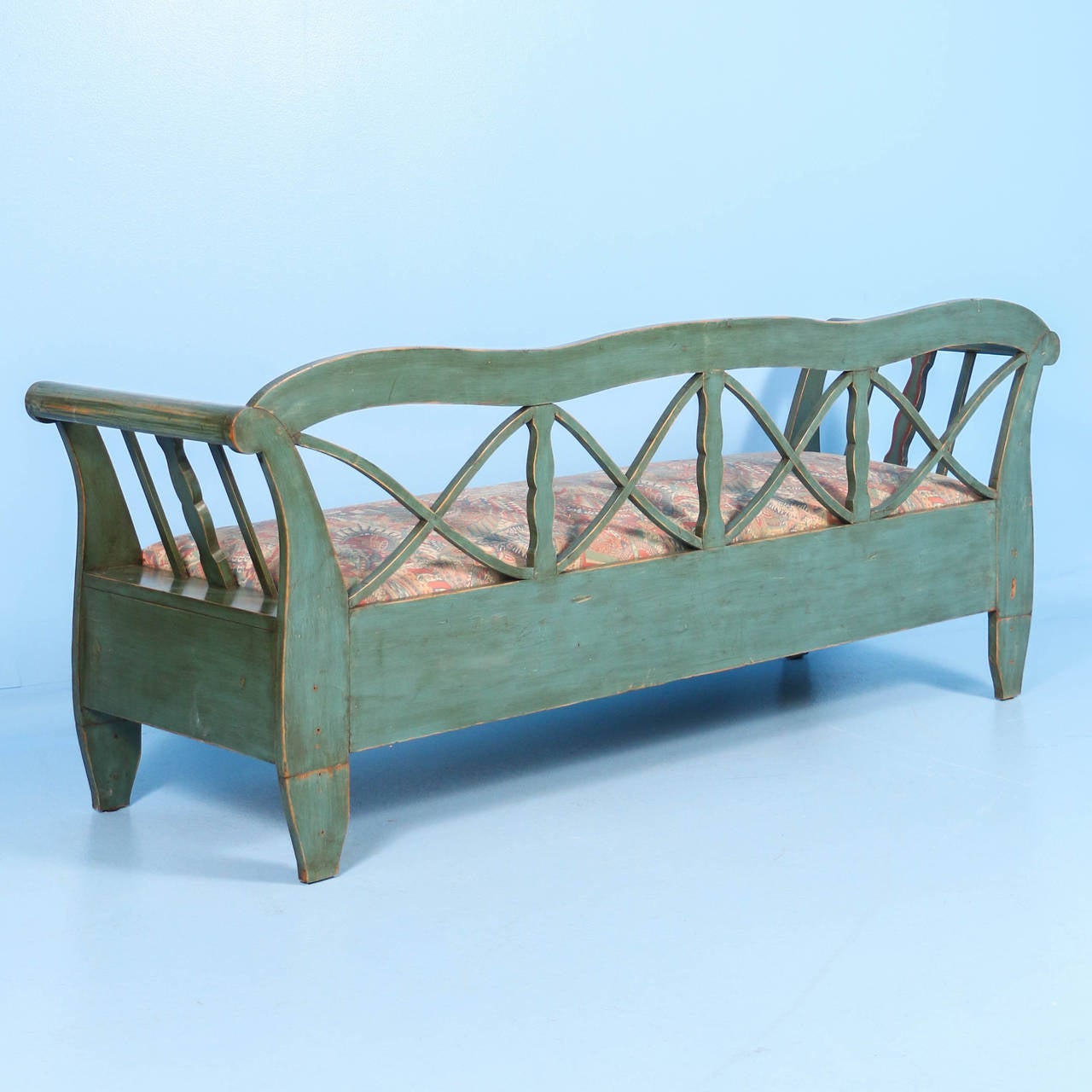 This original painted green Swedish bench is accented with red trim and red and white flowers. The soft color palette is a wonderful compliment to the graceful curves and lattice work back of this pine bench.  Please review the close up photos to