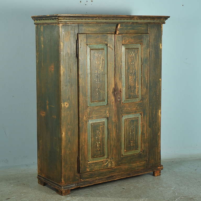 This armoire is an excellent example of Lithuanian folk art at its finest. The original paint style and technique is true to the country regions of Lithuania. The simplistic floral patterns in the panels add to its country charm. The aged patina of