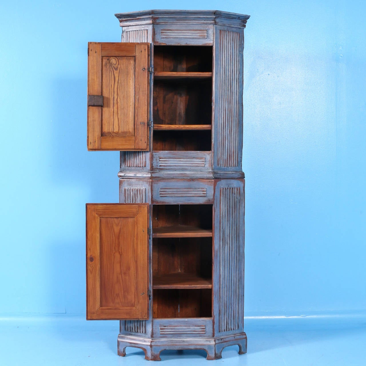 Charming narrow pine Swedish Gustavian period corner cabinet with dentil carved details along all panels. It has recently been given a soft blue painted finish, gently distressed to maintain the Gustavian look of the piece. This is a truly