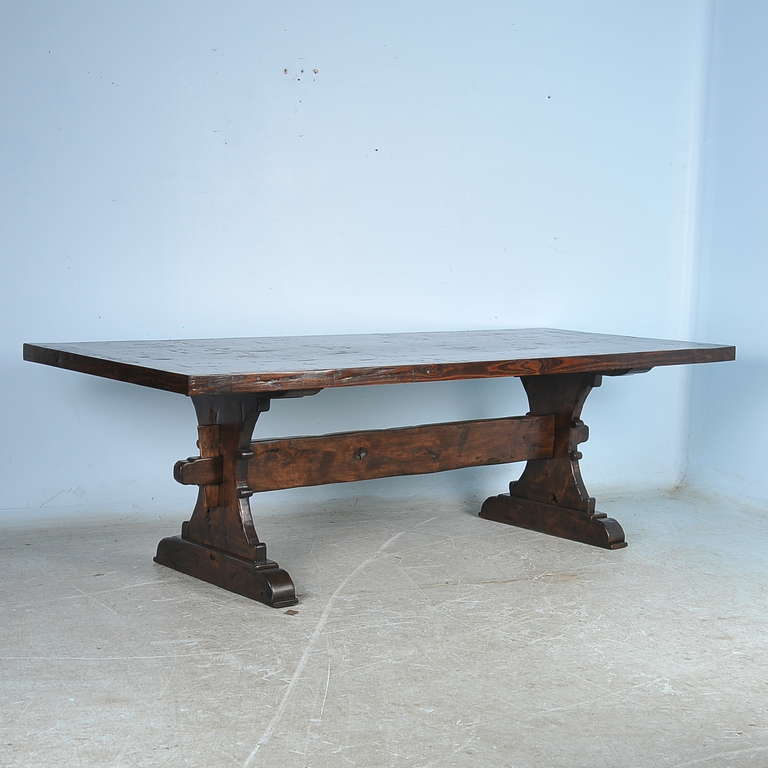 This large dining table is a farmhouse trestle table made from reclaimed wood (note the wonderful aged patina). It has been given a rich, dark finish adding to the visual character and charisma of the table. While most  antique tables had a smaller