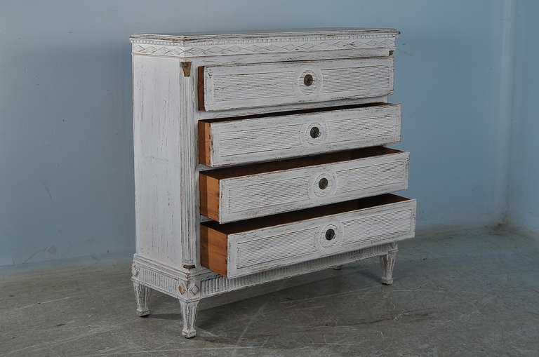 This large chest of four drawers reveals lovely Danish styling with diamond accents, turned columns. carved feet and traditional carving on the drawers. This old pine chest of drawers has been given a new, distressed white finish. This stately piece