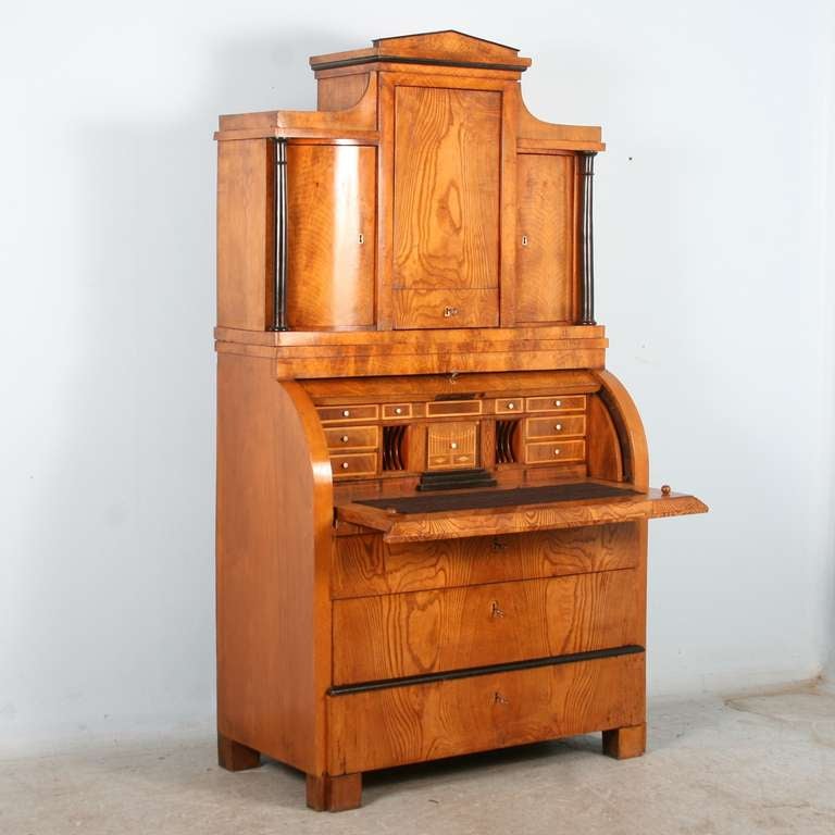 This stunning secretary Is made of elm wood with a shellac finish which brings the wood to life. The wood grain appears to glow from within, and the detailed drawers and classic Biedermeier black columns complete the overall classic look. 

In the