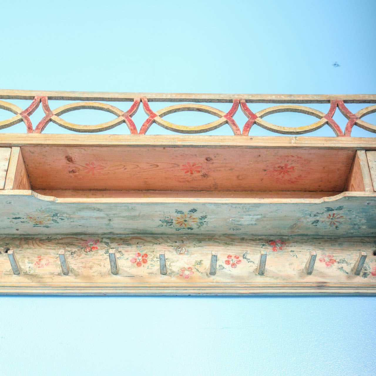 This charming hanging shelf/rack still maintains its original soft white paint, accented with a delightful green leaf and orange/red floral motif. Please examine the close up photos to appreciate the carved details as well. While painted racks were