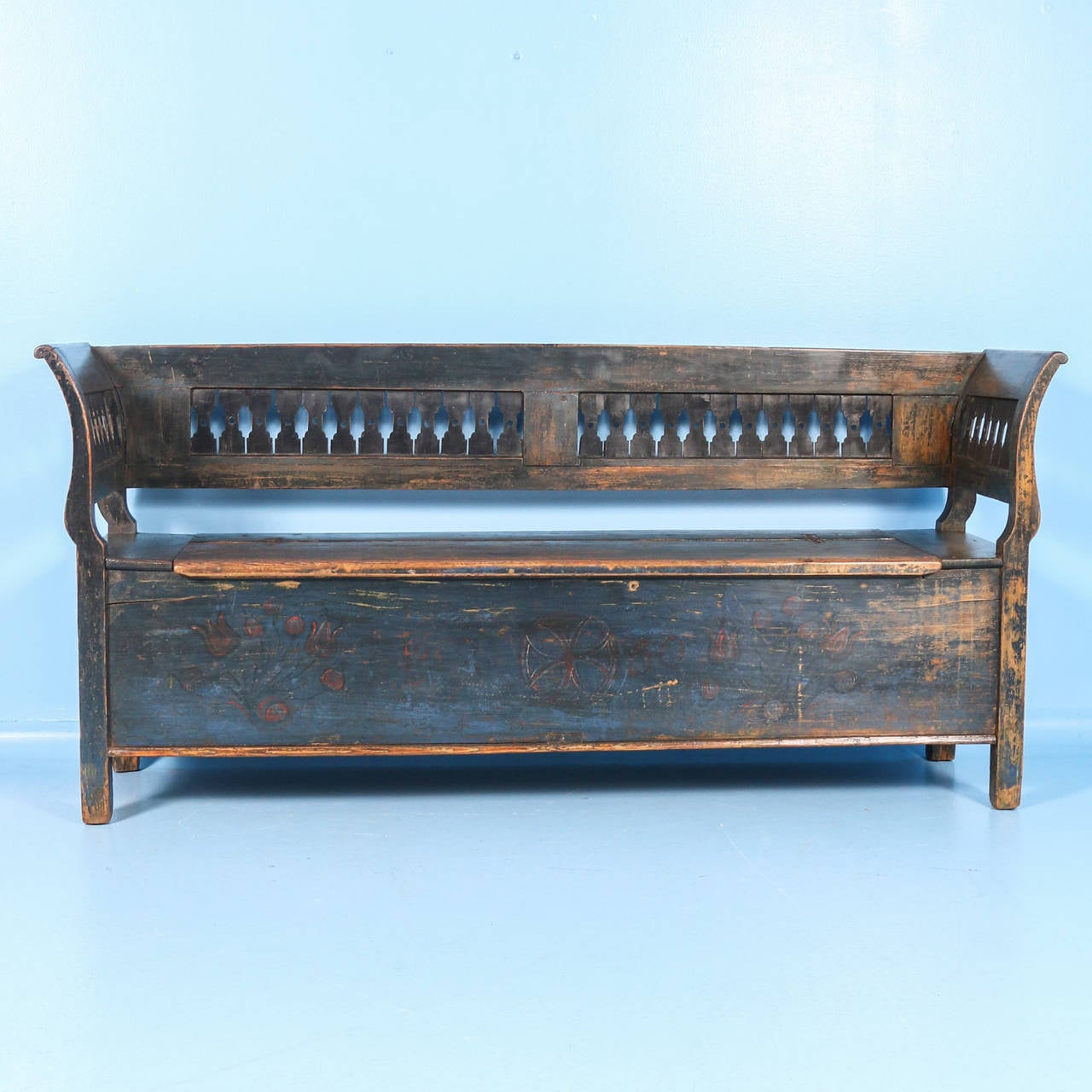 The bench still maintains its dark blue painted finish, gently worn and distressed reflecting the many years of use. On the front, you can still see the red painted tulips/flowers which were a traditional folk art motif during the 1800s. The date of