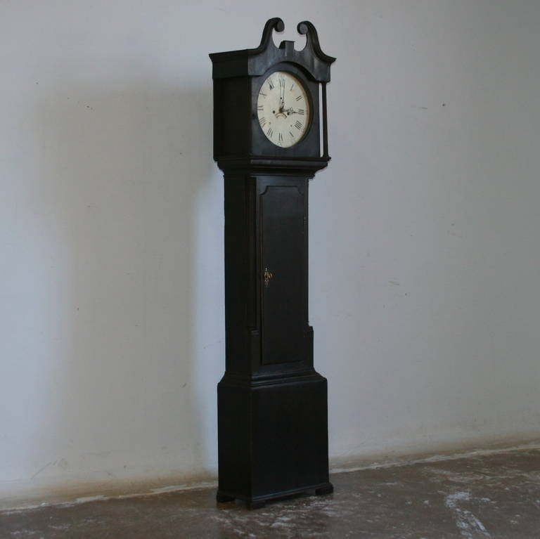 The clean lines of this clock are crowned with a carved bonnet and the clock face has column details on the left and right adding focus to the face itself. The black paint is beautifully distressed, see the close up detail of the corners and edges