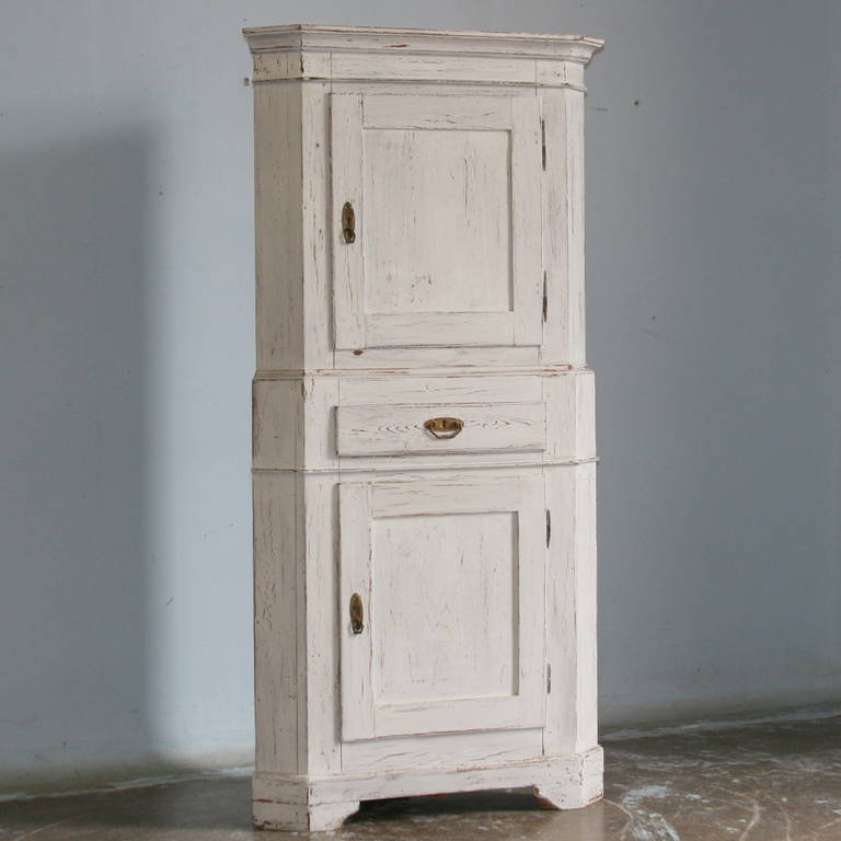 This delightful Swedish corner cupboard was crafted in the 1860-1880s. It is a typical pine piece used in many Swedish country homes, the middle drawer adding a fun element to it. We recently gave it a new distressed white and gray finish. Please