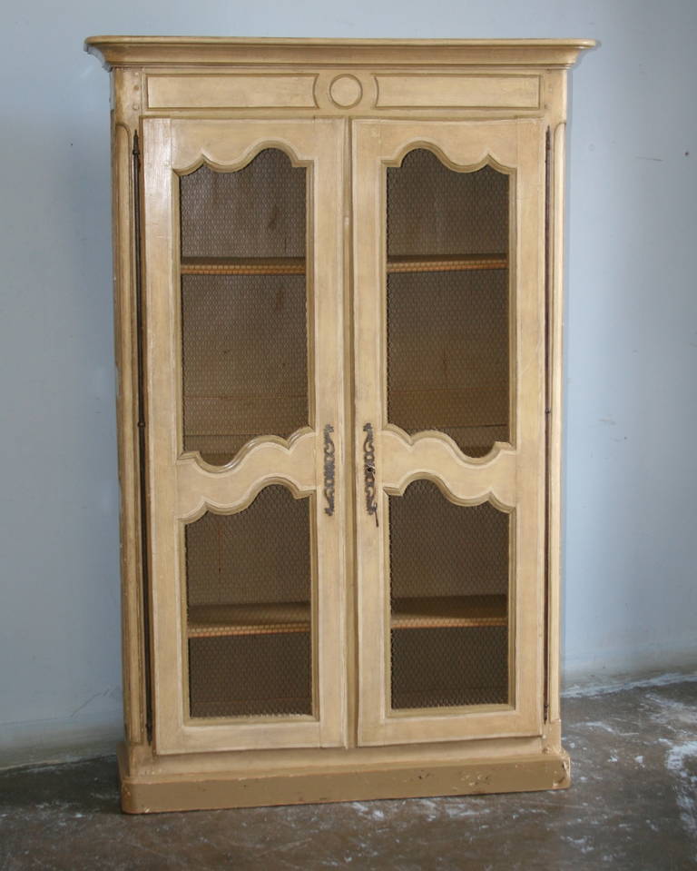 The soft color pallet and curved panels add a romantic touch to this French Country Bookcase. The wire in the panels allows those items inside to casually displayed. Note the wonderful long French hinges and escutcheon plates.