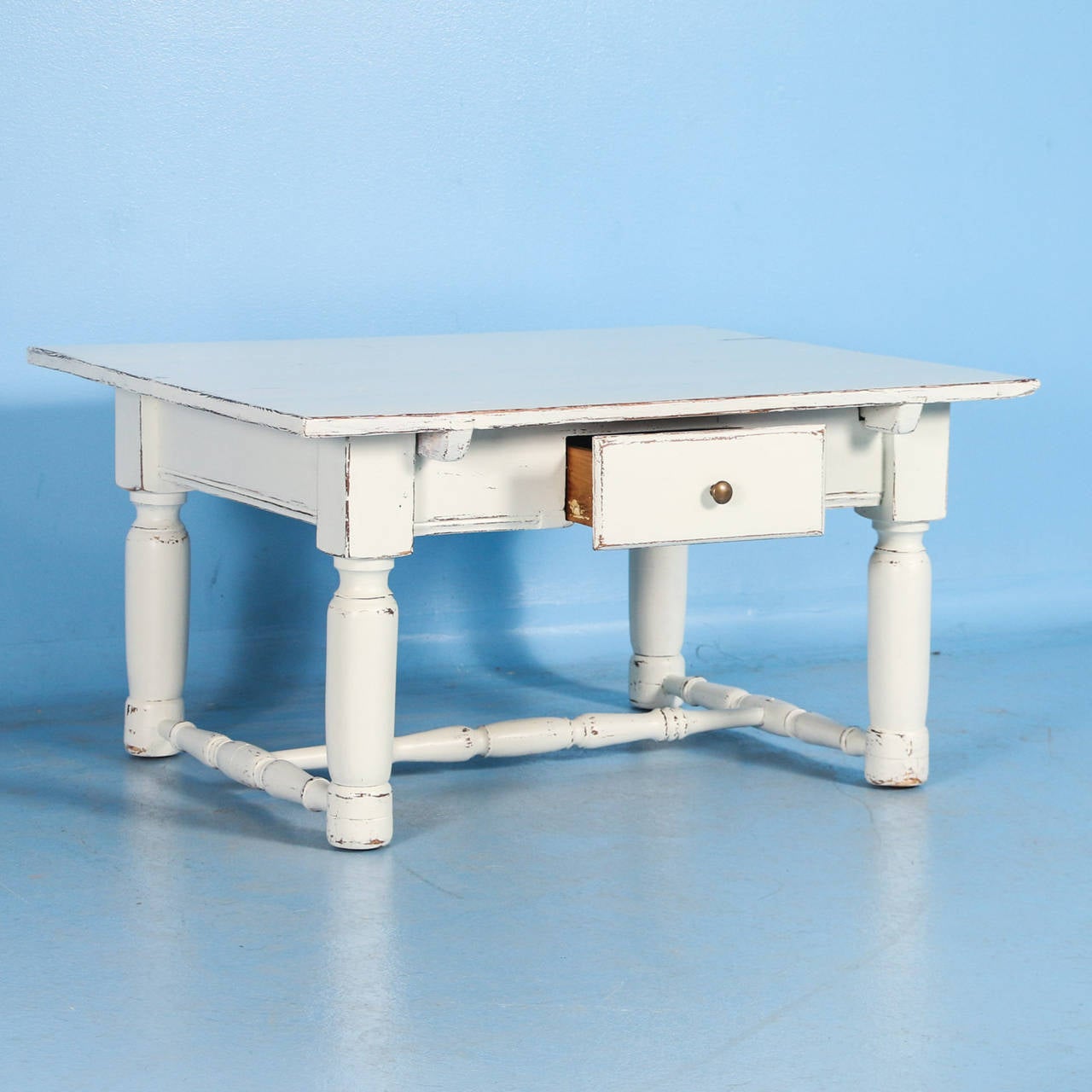 This delightful coffee table has recently been given a white painted finish, adding to the European country charm of the piece. The single drawer and turned stretcher base add to the visual appeal, creating great impact in a small space. The table