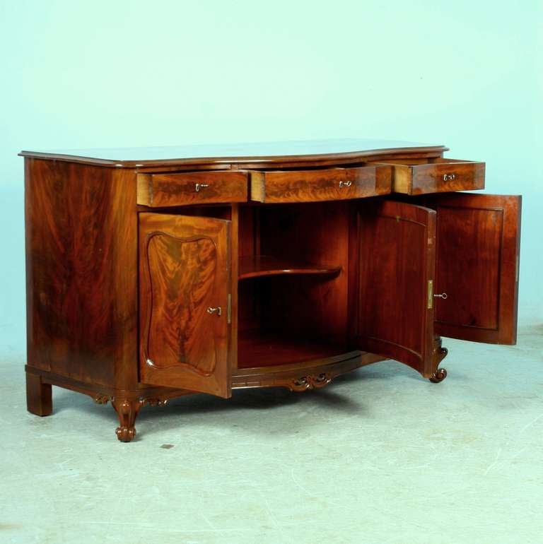 This exceptional sideboard/buffet literally glows from the flame mahogany. Note the beautiful wood detail on each drawer and door which captivate the eye. Within each of the 3 top drawers is a felt lined compartment to store silver. The side drawers