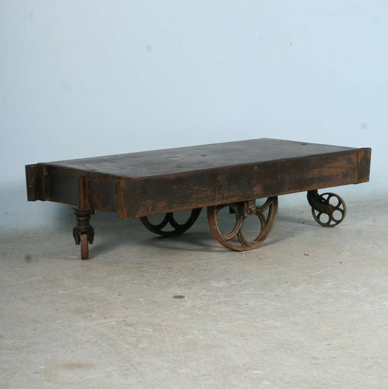 The cast iron wheels of this old metal cart add to the industrial look of this coffee table. Perfect for a vintage look, or great juxtaposition against a very modern setting as well.