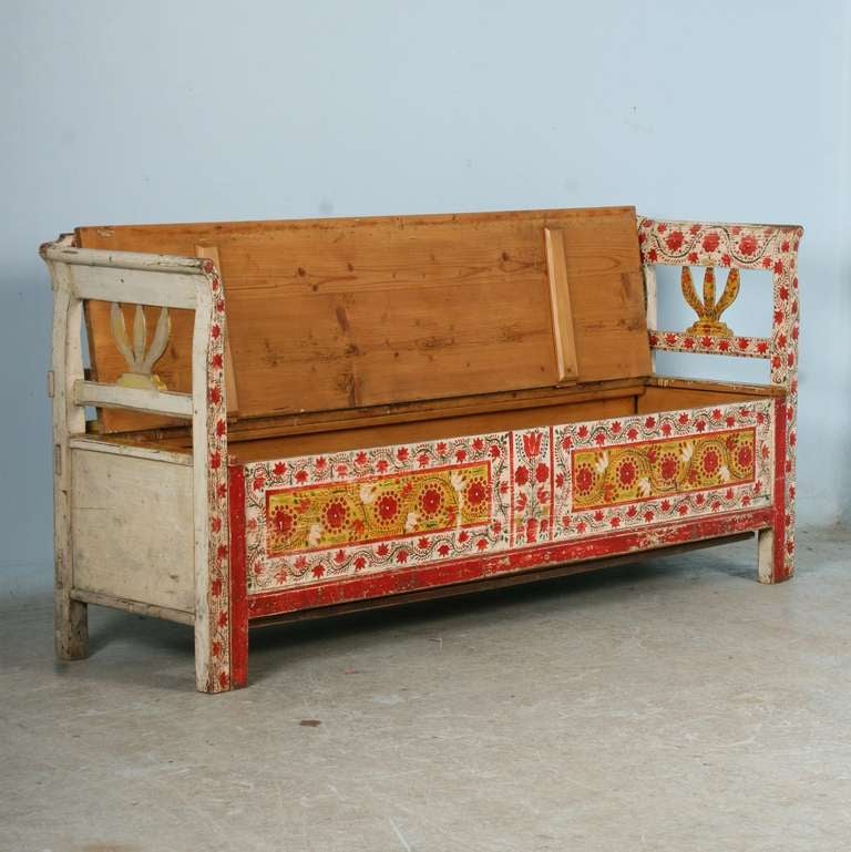 The vivid paint is all original on this whimsical Romanian bench, circa 1880. The red floral and green vine pattern were a traditional folk art pattern of the era. The bench opens to reveal a storage area below. Whether this is used in a hallway,