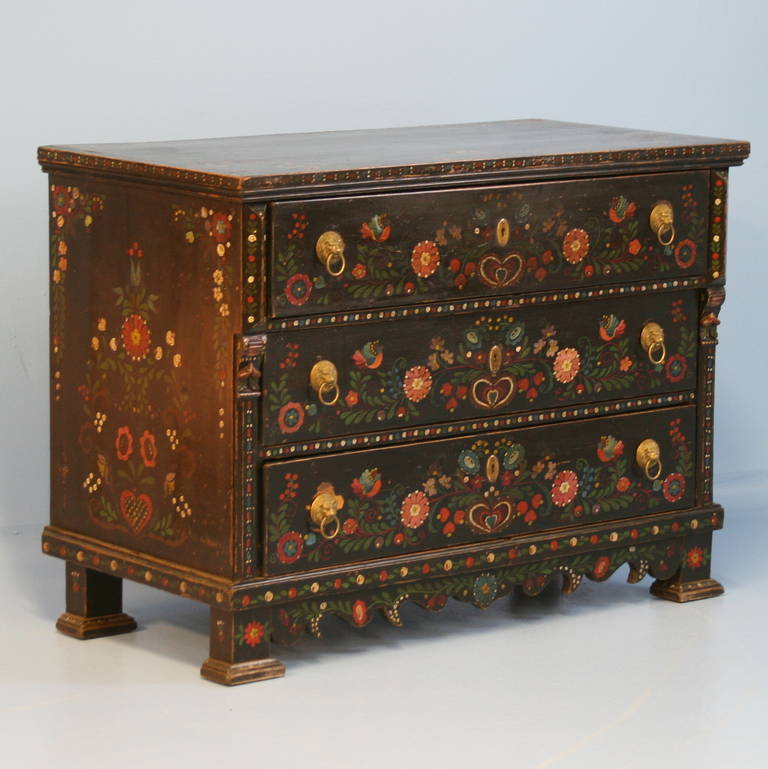 This highly decorative chest of drawers maintains its original folk-art paint. The black background is accented with vibrant details of flowers, birds, vines and other colorful flourishes. The sides and top are painted as lovely as the front.  Note