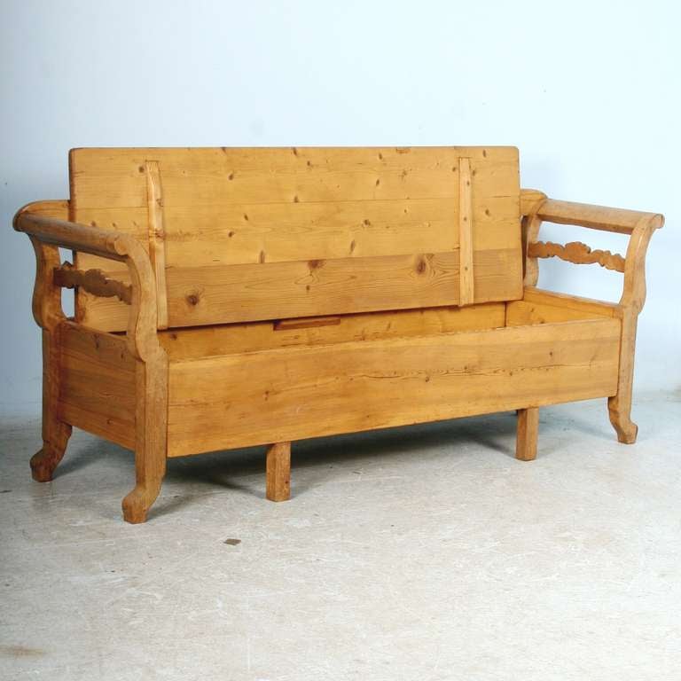 This lovely pine bench is a wonderful example of Swedish country craftsmanship in the Karl Johan design. The gentle curve of the arms and lovely carved details add to its allure. The seat opens to reveal storage space below. Note in the detail