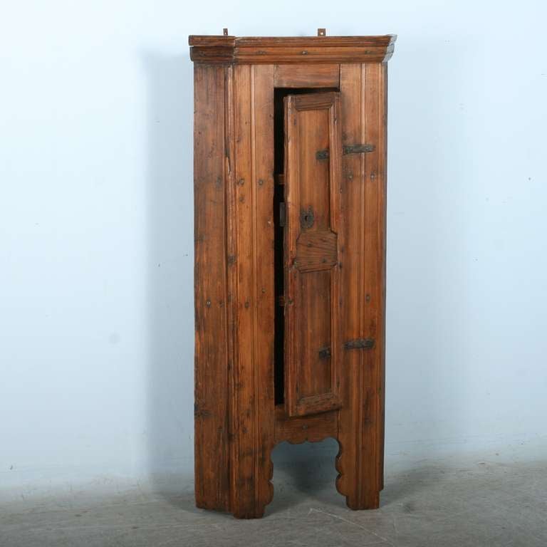 This rustic pine hanging cupboard was a traditional item found in country homes and farmhouses as valuable additional storage before the age of built in cupboards and closets. The primitive appeal of this piece is in the richly aged patina of the