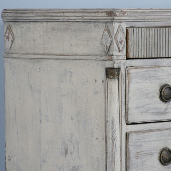 This large chest of 5 drawers reveals lovely Danish styling with diamond accents, turned columns and traditional carving on the top drawer. This old pine chest of drawers has been given a new, distressed white finish. This stately piece will serve