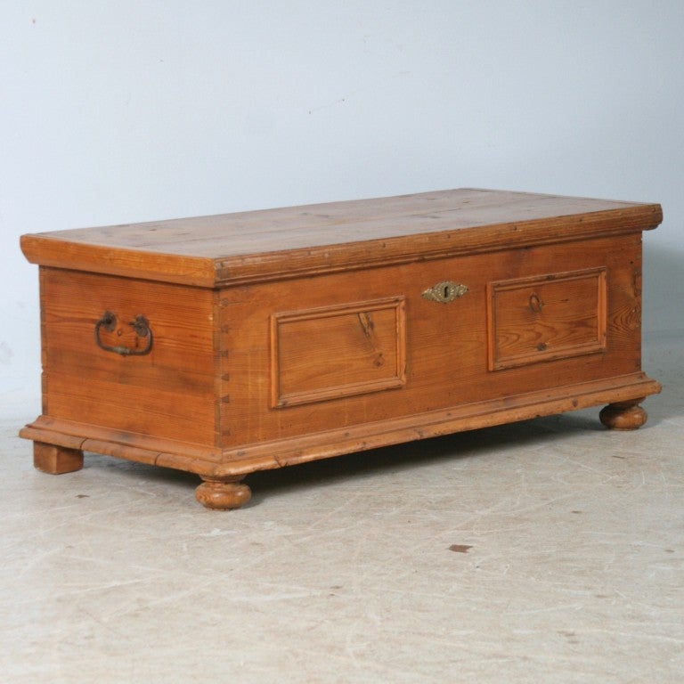 This warm antique pine trunk offers great interior storage and would serve perfectly as a small coffee table. Note the dovetail corners, wrought iron handles, and panel trim on the front that add character to this charming piece.