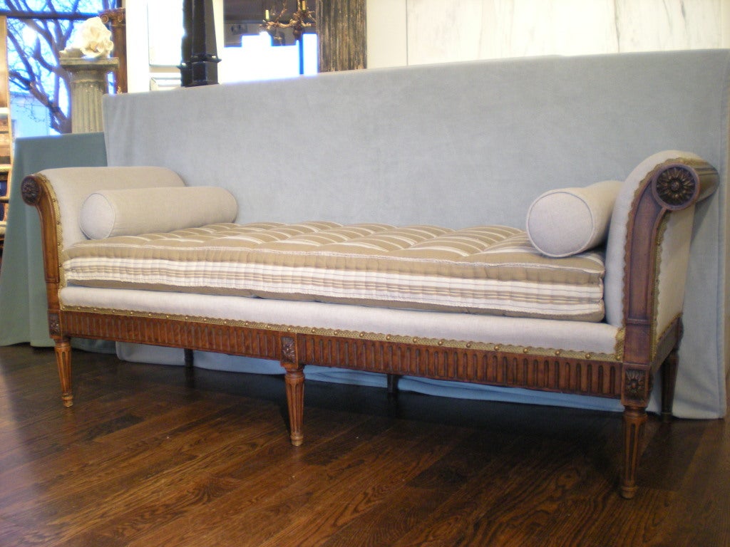 Carved walnut daybed/bench with serpentine curved front; finished on all sides; vintage French ticking mattress with down