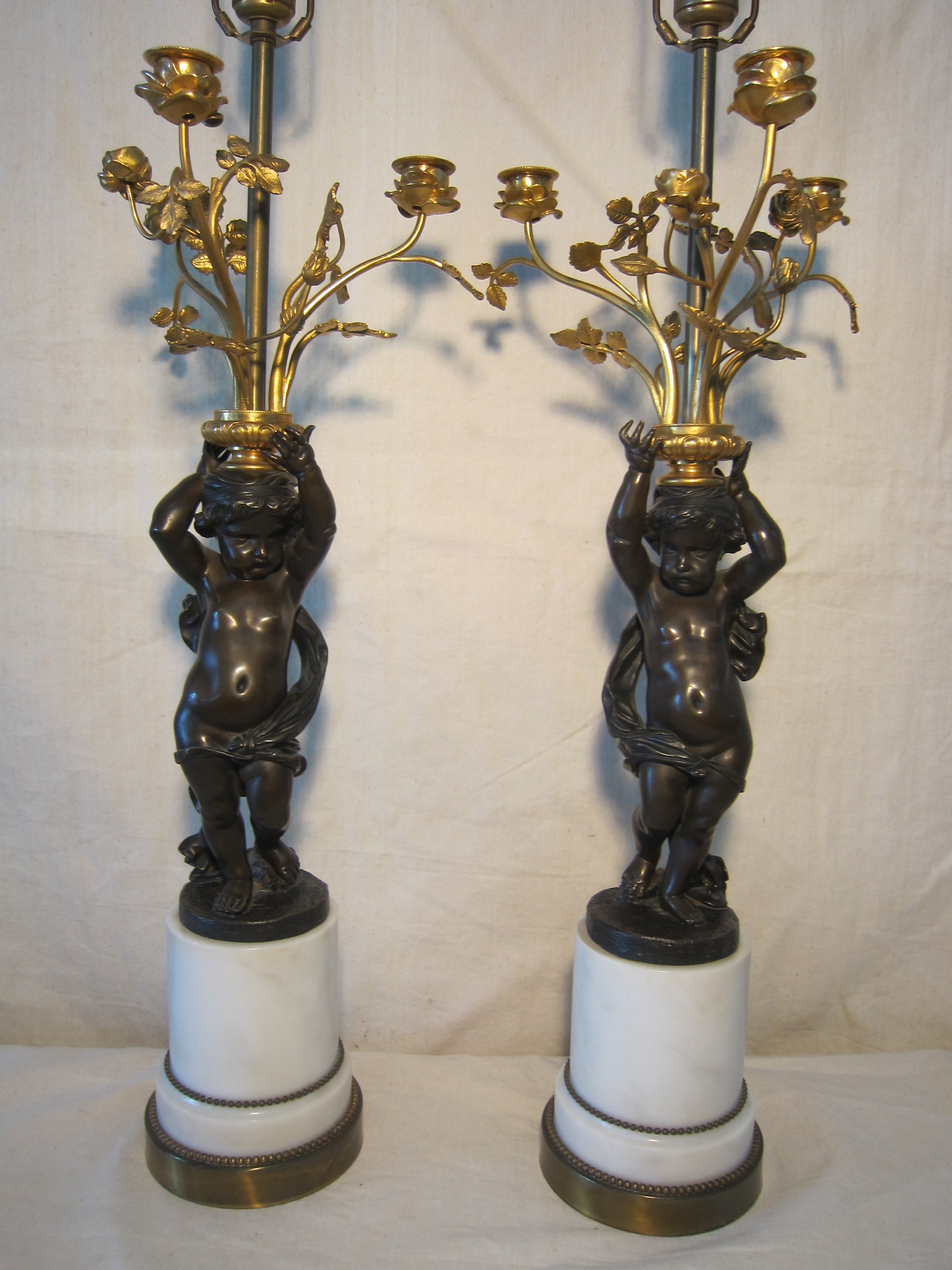 Spectacular Pair of 19th century French Gilt Bronze Putti candelabra lamps.
Original marble socle bases. True pair A left side and A right sided image. Each Bronze has it differences. Variations can be seen also in the fingers, the hands, hair, 