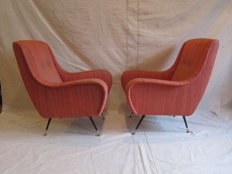 Pair of Italian Mid-Century sculpted lounge/armchairs.
Exceptional style and comfort. 
Splayed black metal legs with brass sabots. 
Chairs need re-upholstery.