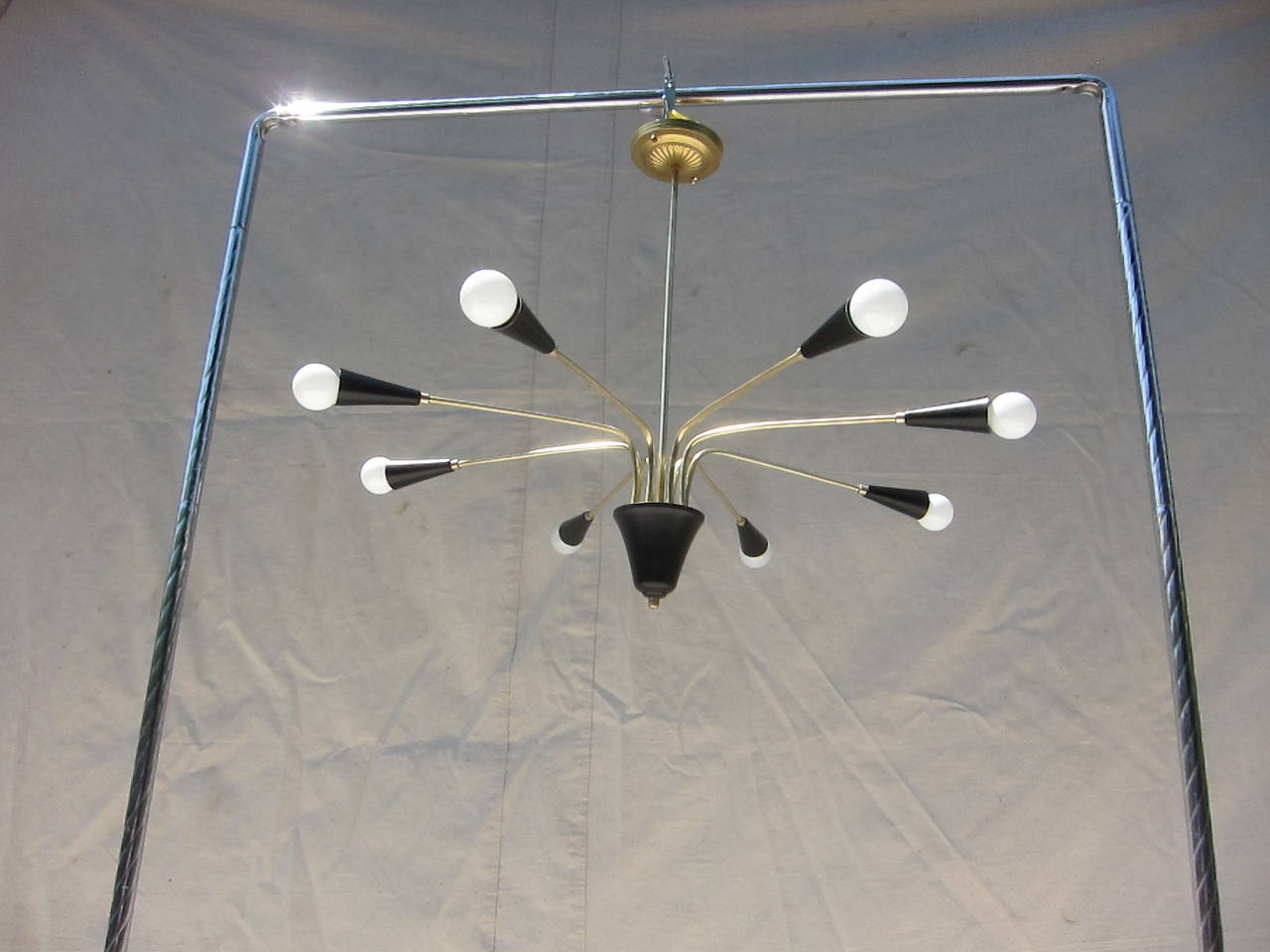 An Eight Arm Brass hanging Lamp in the style of Stilnovo.  Very good condition, some irregularity to the brass arms bends (not of noticeable concern), newly rewired.  Canopy and height can be customized for your space and hieght requirements. 
CA