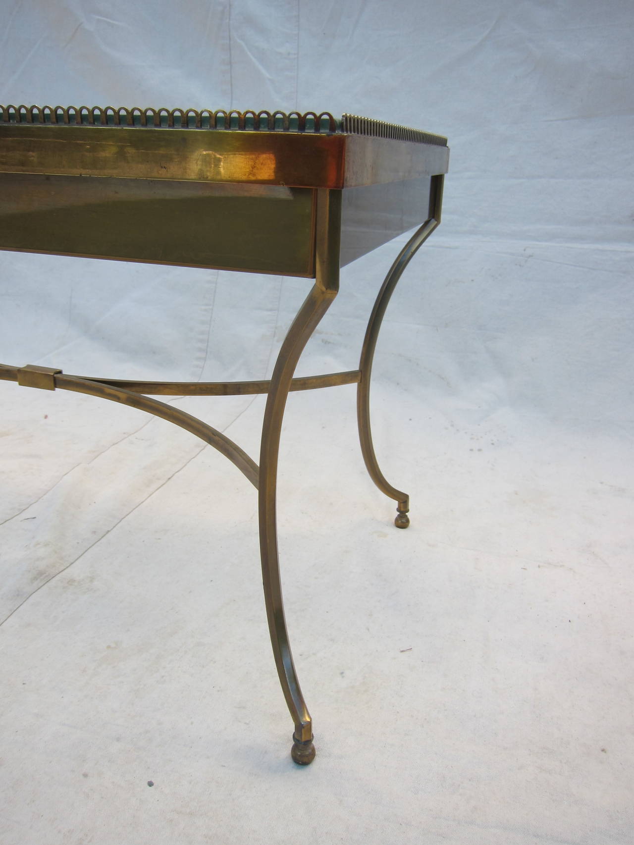 20th century brass table with two shelfs of glass, a tray top with galleried edge detail, and display space. Wonderful solid brass small-scale cocktail table with compartment or tray use. Top removes when pulled up with light force.  Very good