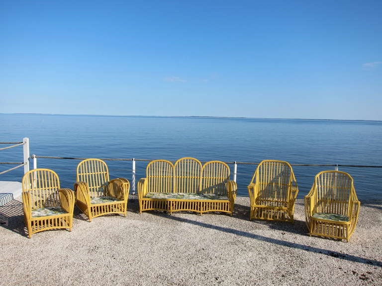 Antique stick wicker set comprised of one sofa, four chairs and one table - all in yellow paint.  Additional sofa, chair, table and chaise available in separate lot.  Large scale and dramatic lines.