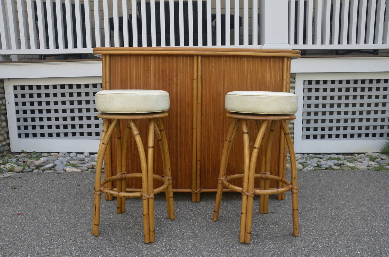 Mid-Century Heywood Wakefield bar and bar stools with built in shelves. Top of bar is beige formica and swivel seats are matching beige vinyl.