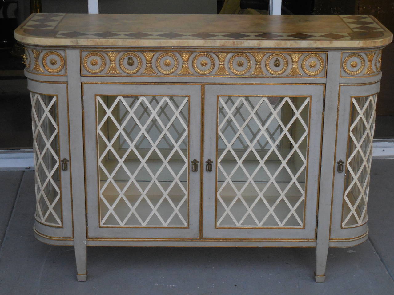 Exquisite cabinet or console. Gilt detail and faux marble-top. There is a glass shelf behind the central doors and also on the corners. Interior is mirrored and lit.