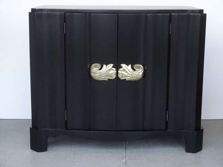 Exquisite cabinet with serpentine doors and large solid brass pulls. The 2 sculpted doors open to reveal a removable shelf.