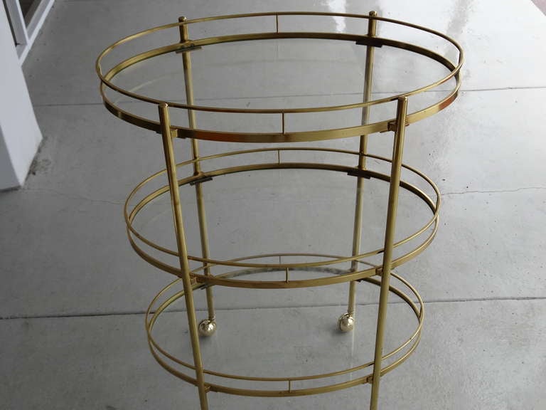 A mid century triple deck bar cart. Brass construction with glass shelves. Very rare and chic.