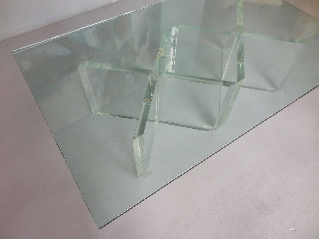 A great looking coffee table by John Mascheroni. Four thick Lucite angular bases, support the glass top. Signed on Lucite. Glass top has rounded corners. Bases could also be arrange in other configurations. Lucite is 1.5