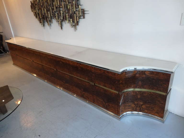 A unique 1970s sideboard. Every single inch is exquisitely crafted. Stainless steel molding and recessed brass band and pulls. Note the perfectly matched veneer and stainless molding. Lots of drawers, some fitted with extra compartment. Both corners