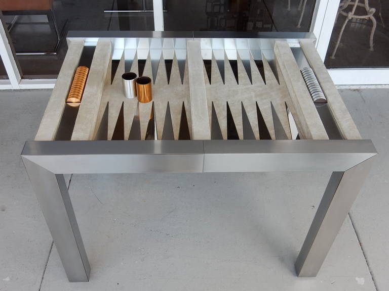 Beautifully crafted backgammon set. The frame is clad in stainless steel, suede top with SS insets brass and SS chips and cups. Chips have leather bottoms and cups are leather lined. Comes with protective Lucite top.