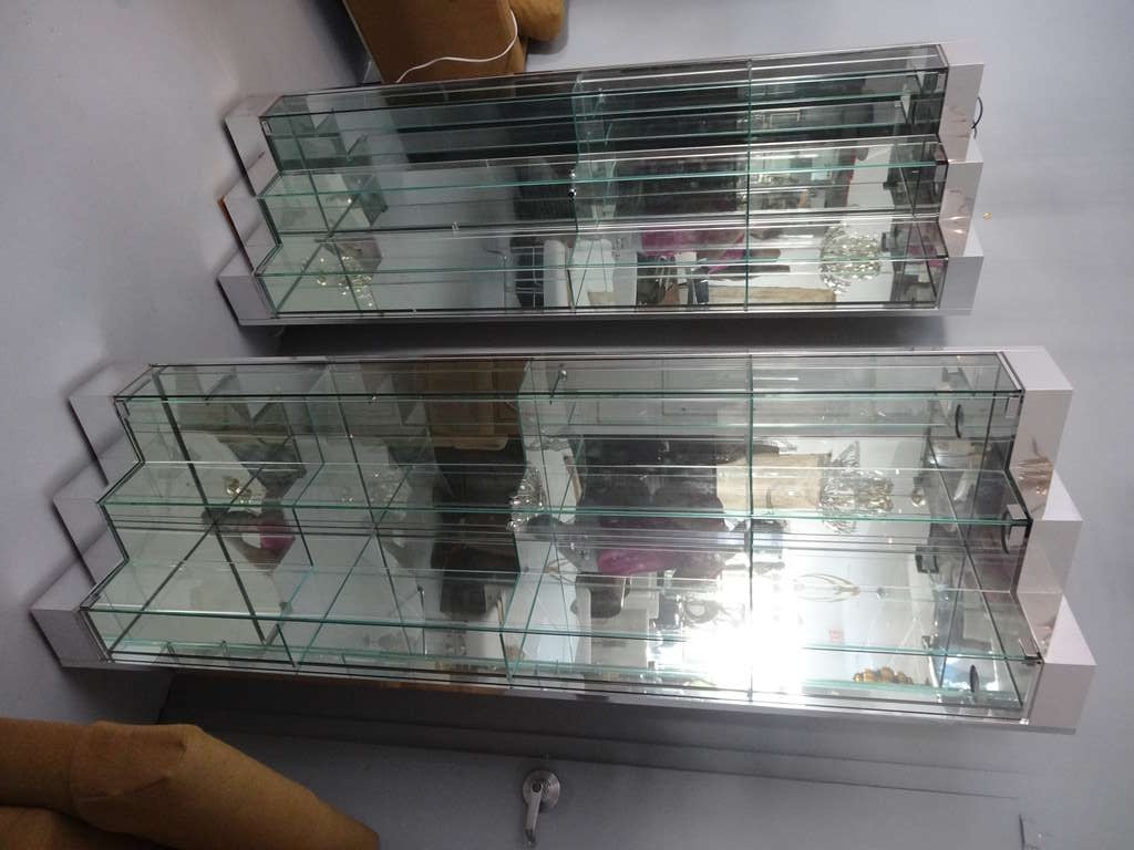 A pair of vitrines by Ello. Done in chrome metal with mirrored backs and glass shelves. 2 front doors each. Very interesting yet functional. Could be used as corner pieces or together for a large showcase. Both are lighted at the top.