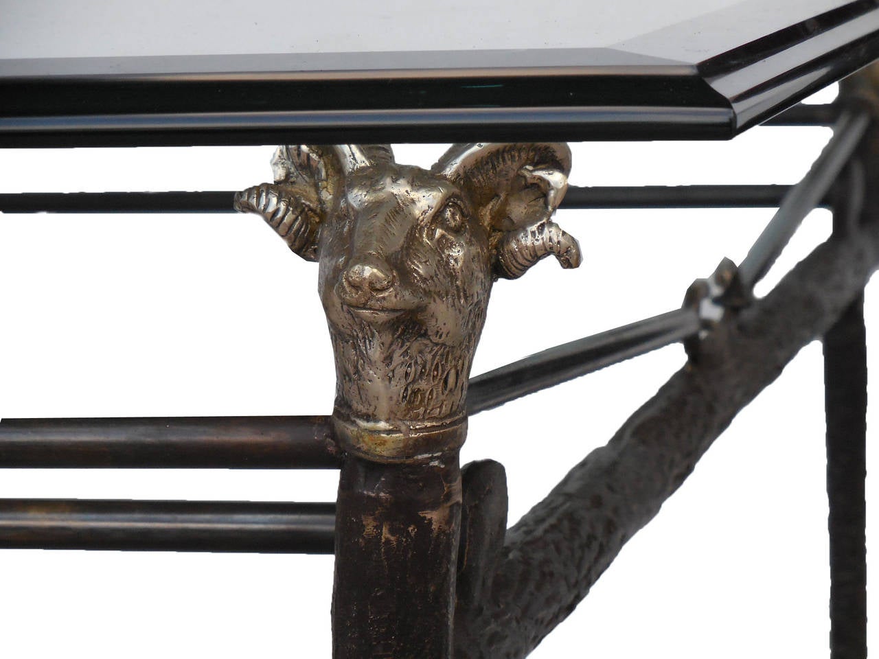 A bronze coffee table with a glass top supported on ram heads. Two tables  available.