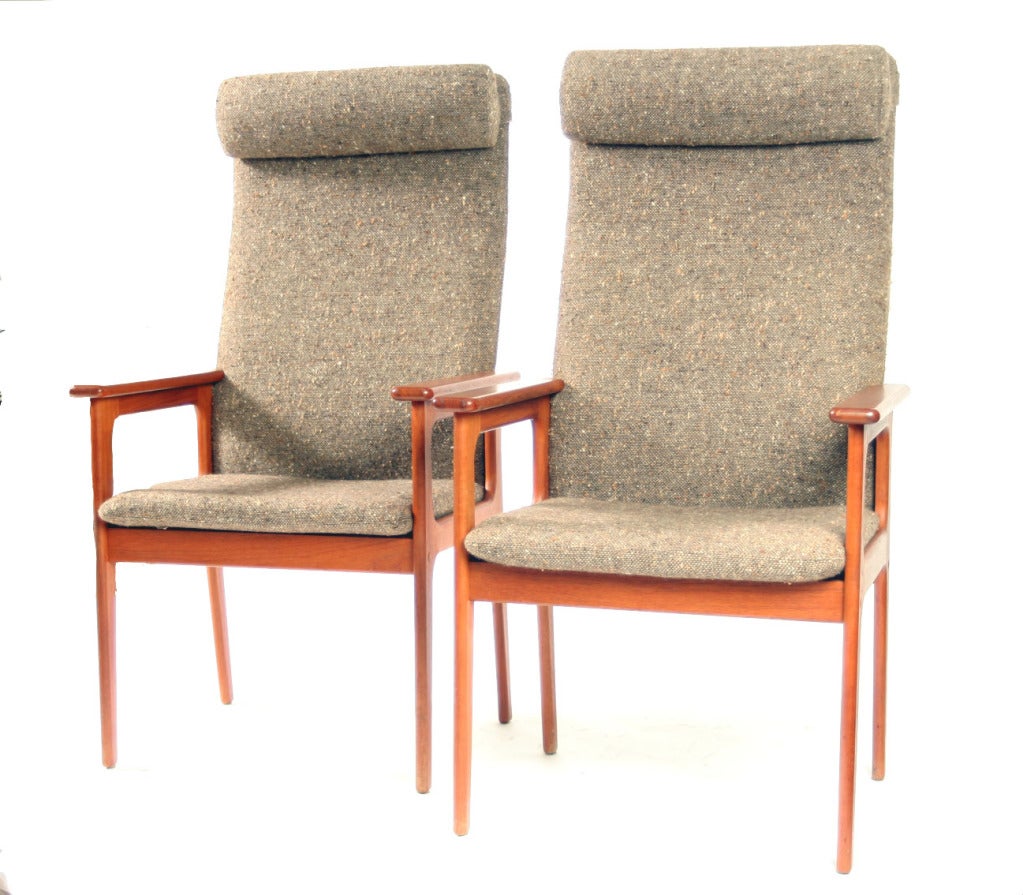 A striking pair of late 1970's teak framed high backed arm chairs with woven textured fabric. The height and thin curvature of the back gives the chairs a marked elegance and unsurpassed comfort.