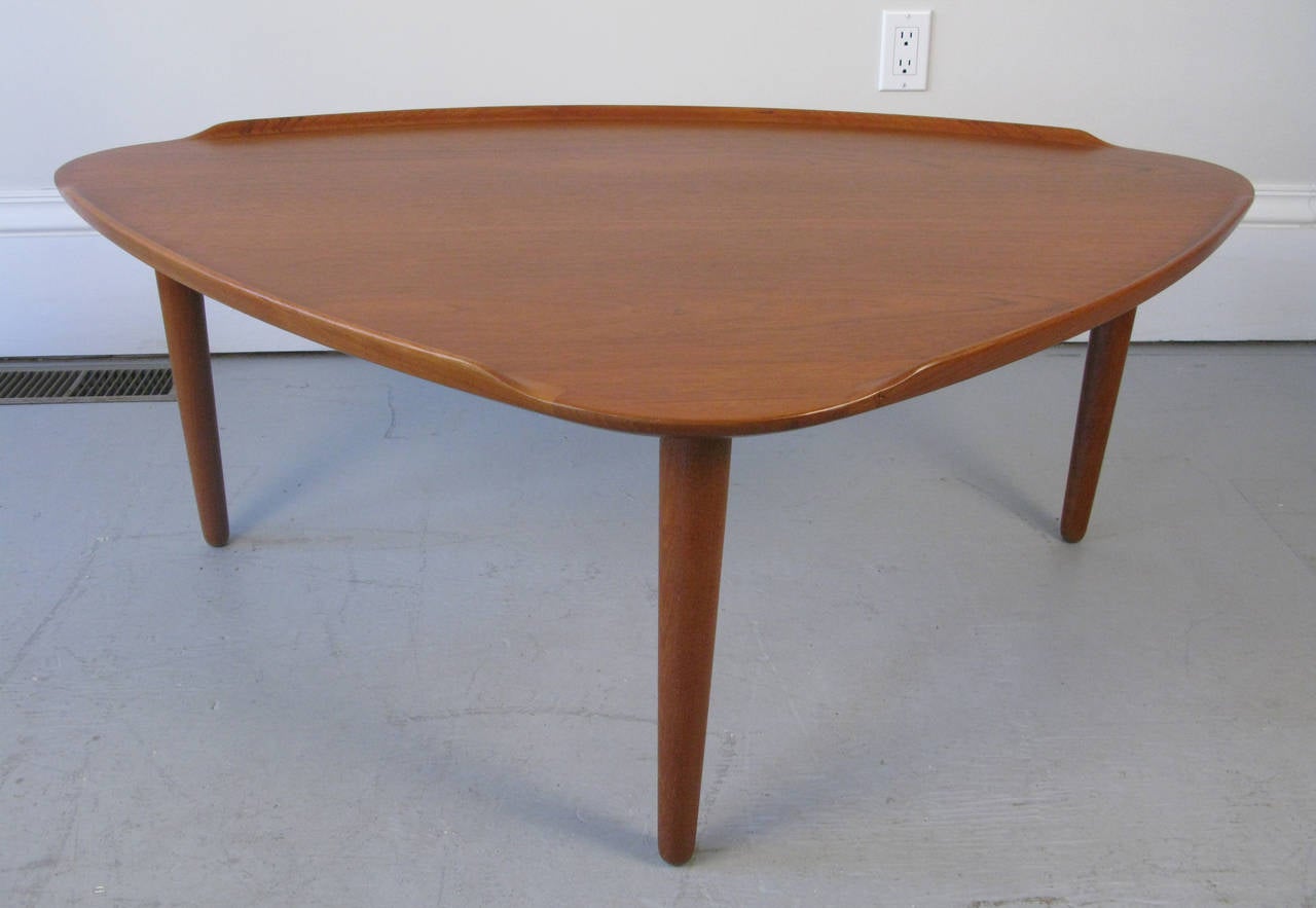 Wonderful triangular teak Danish coffee table. Elegant with it's thin top and raised curved edges. The table could also have use as an end or side table. The table has been cleaned and polished.