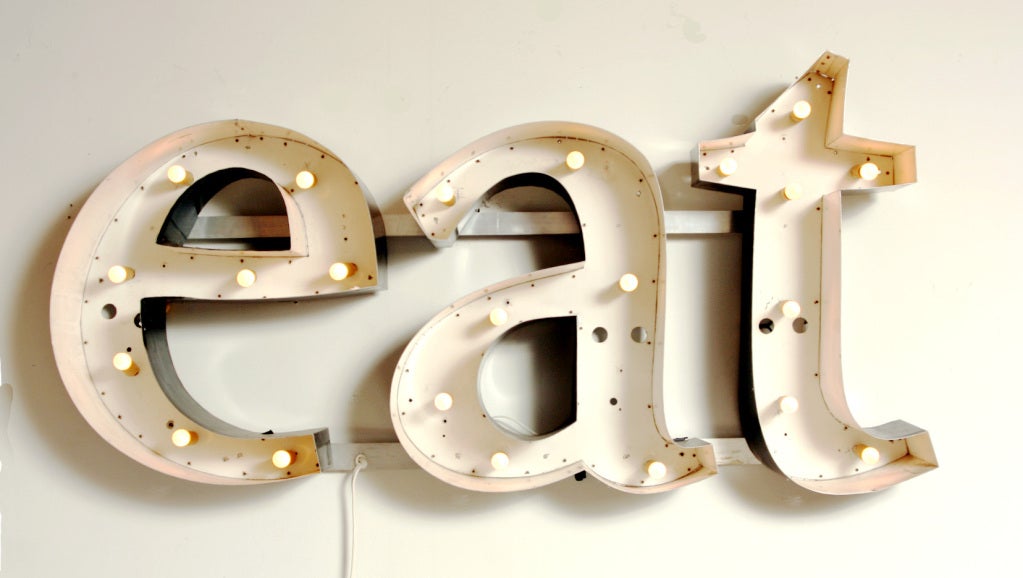This vintage sign features aluminum channel letters mounted on two horizontal aluminum brackets and can be wall-hung or free standing.  The neon tubes have been removed and replaced with warm incandescent bulbs.  It would look fabulous in any