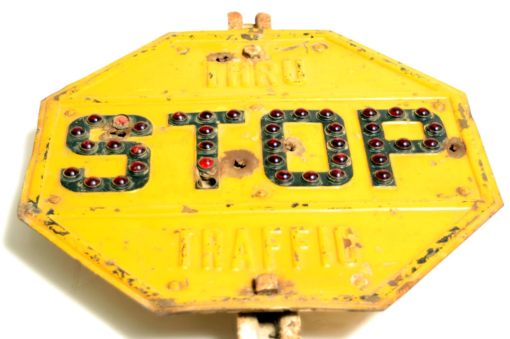 A bright yellow stop sign with red glass reflectors from the first part of the 20th century.
The sign has a very 60s Pop Art  feel about it.