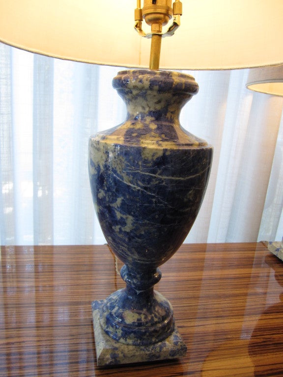 Pair of table lamps in a classical urn form carved from solid pieces of blue sodalite, a mineral similar in look to lapis lazuli.  Since these are solid stone, they are quite heavy.