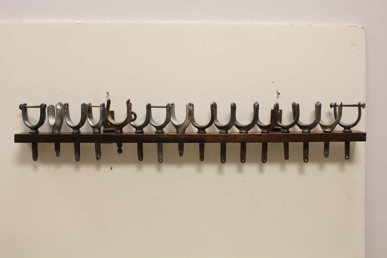 Collection of 16 metal oar locks on original wooden holder.