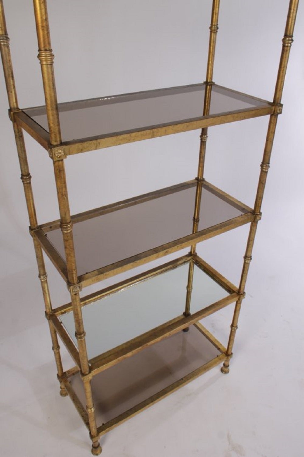 Pair of stylish Regency style gold leaf Etageres with smoked glass and one mirrored shelf.