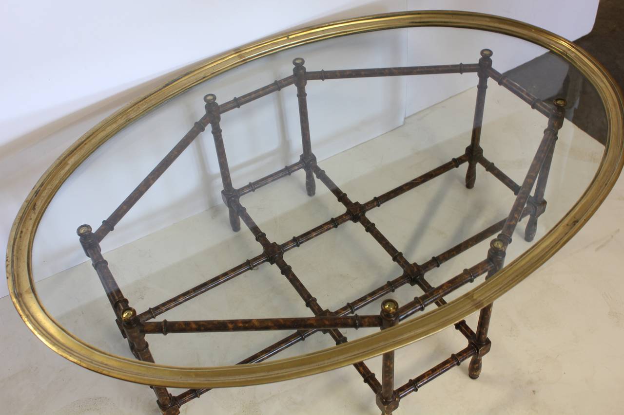Stylish faux bamboo coffee table with brass rimmed glass top designed by Baker.