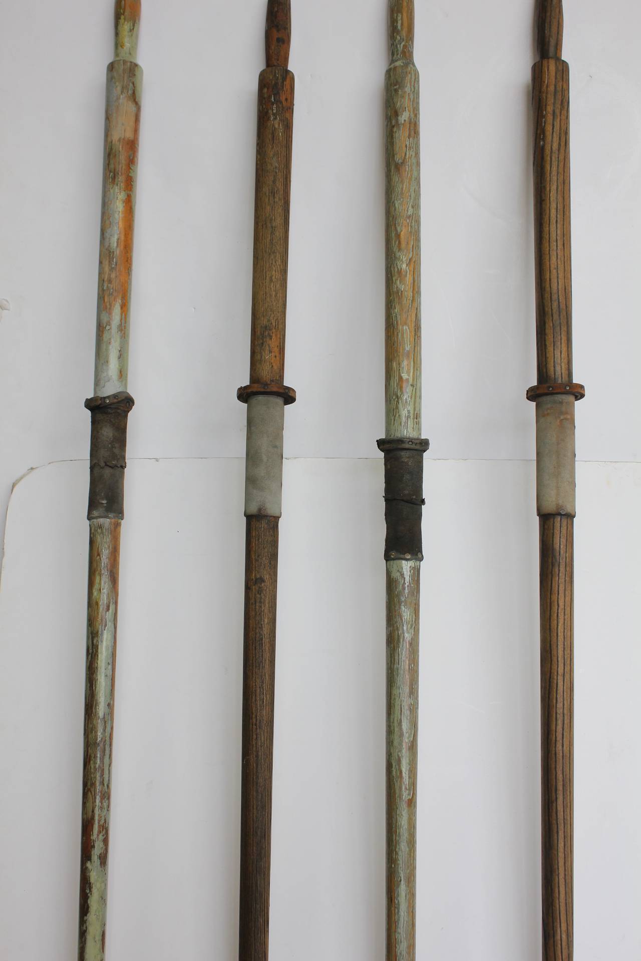 Collection of vintage wood oars with leather holders.