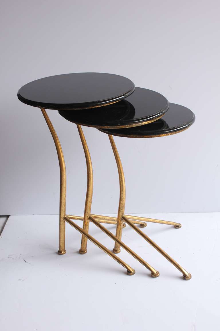 Stylish modern nesting tables with gold leaf bases and lacquered tops.