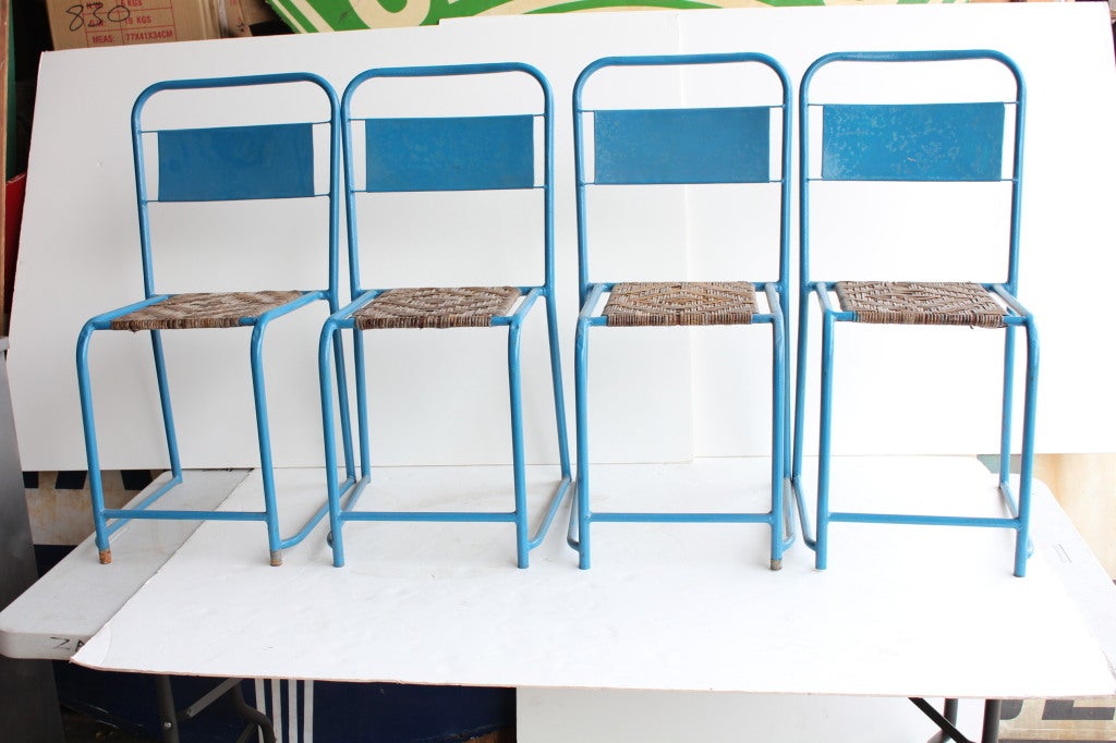Mid Century metal bistro chairs painted in vibrant blue tone with rattan seats. Price for each chair.
