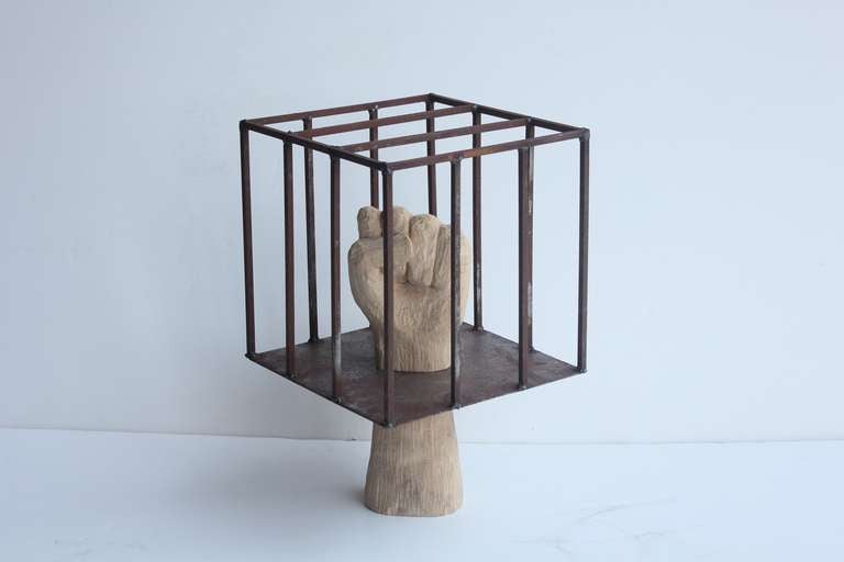 Contemporary wooden hand sculpture in metal cage.
